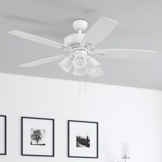 a white ceiling fan in a room with pictures on the wall