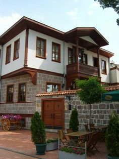 the house is made of stone and has wood trimmings on the windows, doors, and balconies