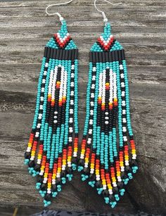 two pairs of beaded earrings sitting on top of a piece of wooden planks