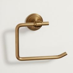 a brass toilet paper holder on a white wall with a gold colored metal towel ring