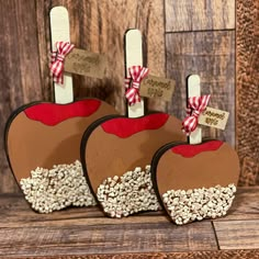 three wooden apples with red and white decorations