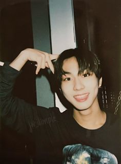 a young man posing for the camera with his hand on his head and wearing a black shirt