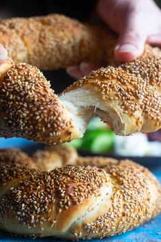 sesame seed bagels are being held by someone's hand over a blue plate