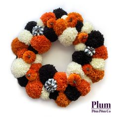 an orange, white and black pom - pom wreath on a white background