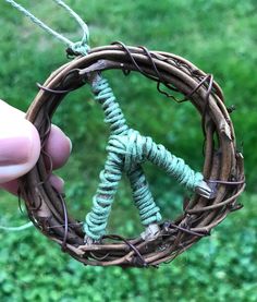 someone is holding up a wreath made out of twigs and twined with green cords