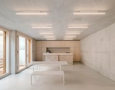 an empty room with white tables and benches