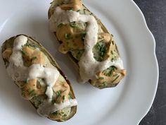 two pieces of bread covered in sauce and green onions on a white plate with a black background