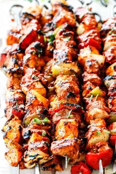 skewered chicken and vegetable kabobs on a white platter with tongs