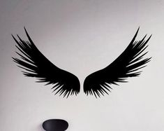 a wall with black wings on it next to a white wall and a round mirror