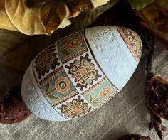 an easter egg sitting on top of a table next to leaves