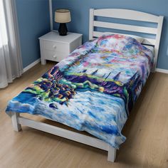 a bed with a colorful comforter on top of it next to a night stand