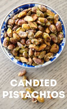 a bowl filled with pistachios on top of a wooden table