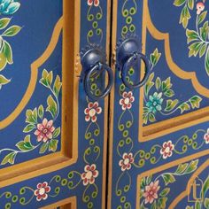 an ornate painted cabinet with two handles and knobs on the front, one door is open