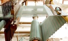 a close up of a weaving machine with people in the background working on it's sides