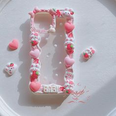 the letter e is made up of hello kitty decorations and beads on a white plate