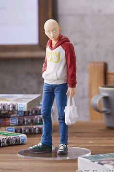 a figurine is standing on a table with books and magazines in the background