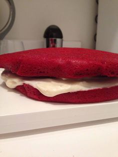 a red sandwich with white frosting on it sitting on top of a counter next to a blender