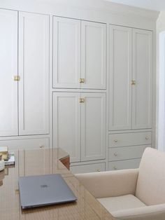 a laptop computer sitting on top of a desk in a room with white cupboards