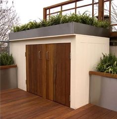 an outdoor storage shed with plants growing on it's roof decking and wood flooring