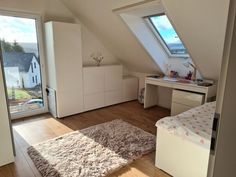 a bedroom with a bed, desk and window in it's attic dormer