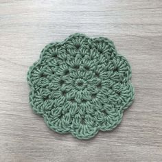 a green crocheted flower sitting on top of a wooden table