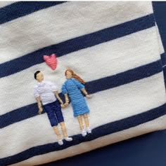 two dolls sitting on top of a blue and white striped pillow