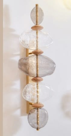 a wall light with three glass balls hanging from it's sides and a wooden pole in the middle