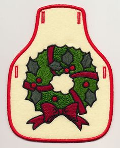 a pot holder with a christmas wreath and holly berries on the front in red, white and green