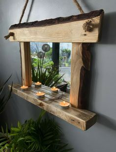 a wooden shelf with candles hanging from it's sides and a window in the background