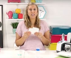 a woman standing in front of a desk holding a piece of paper