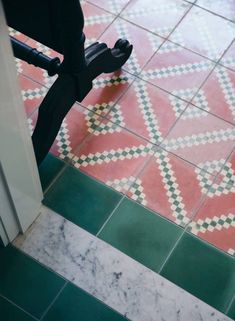 an umbrella is on the ground in front of a tiled floor with green and red tiles