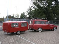 an old red van is parked in a parking lot next to a small camper