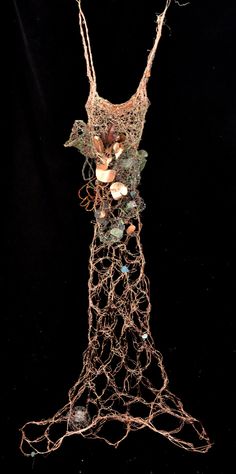 a wire sculpture with many different items on it's body and hands in the shape of a dress