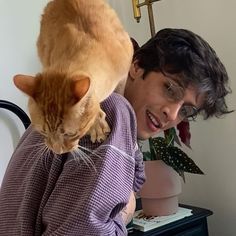 a cat sitting on the back of a person's shoulder while they both look at something