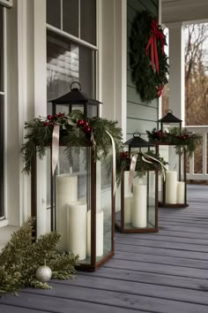 candles are lined up on the front porch for christmas time decorations and wreaths to decorate