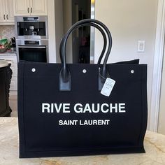 100% Authentic With Tags Still Attached Never Carried Saint Laurent Rive Gauche Tote Bag In Black With White Lettering. This Is A Great Everyday Bag, Diaper Bag, Or Work Bag. This Is The Large One. No Trades Do Not Ask. Saint Laurent Rive Gauche Tote, Saint Laurent Bags, Rive Gauche, Chanel Deauville Tote Bag, Work Bag, Everyday Bag, Purse Wallet, Diaper Bag, Ted Baker Icon Bag