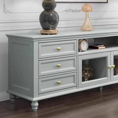 a large gray entertainment center with drawers and two clocks on it's sideboard