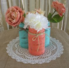 three mason jars with flowers in them sitting on a doily