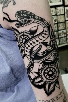 a man's arm with a snake tattoo on it and flowers around the arm