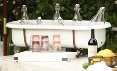 bottles of wine are sitting in front of an old bathtub with lemons and limes