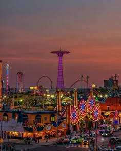 an amusement park at dusk with ferris wheel and rides