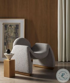 a white chair sitting on top of a hard wood floor next to a framed painting