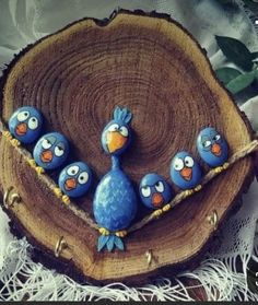 three blue birds sitting on top of a piece of wood