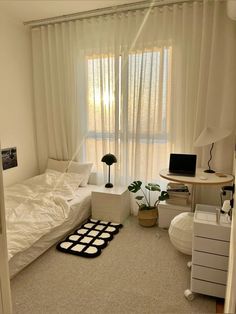 a bedroom with a bed, desk and computer on the floor in front of a window