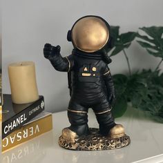 a small black and gold astronaut figurine on a table next to some books