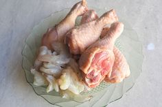 raw chicken legs and onions on a glass plate