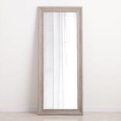 a large mirror sitting on top of a wooden floor next to a white wall in an empty room