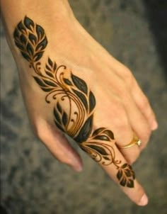 a woman's hand with a black and gold design on the left side of her arm