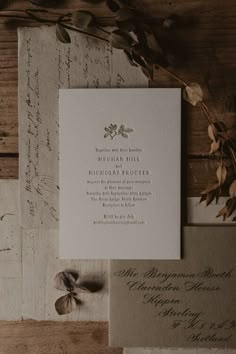 the wedding stationery is laid out on top of some old letters and paper with leaves