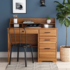 a wooden desk with a chair next to it and a potted plant on top